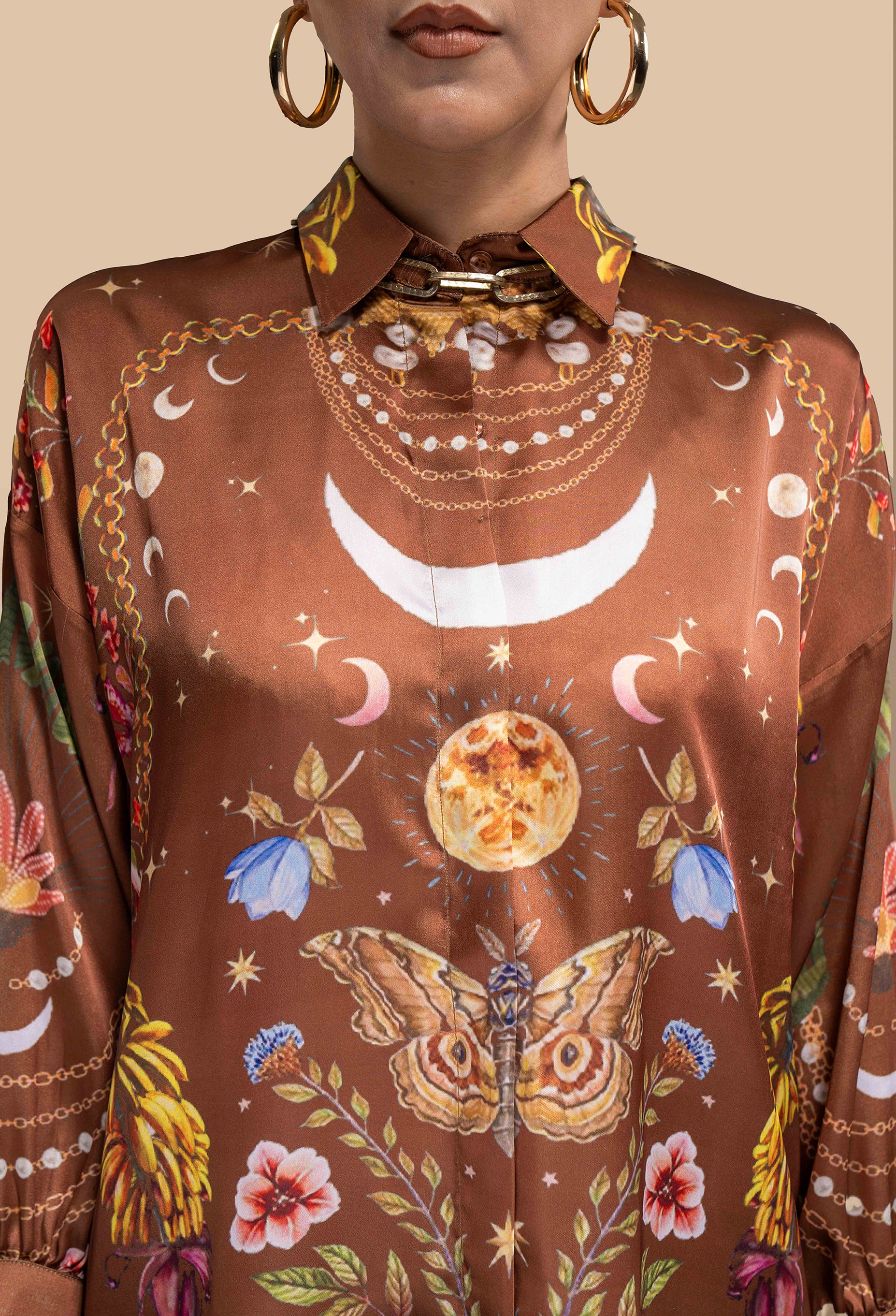 A close-up of the Cosmic Print Silk Blouse, focusing on the intricate cosmic print. The silk fabric shines with a luxurious finish, and the blouse features a high collar with subtle button detailing, adding sophistication to the bold design. The cosmic print's vivid colors and swirling patterns evoke a sense of outer space and wonder.